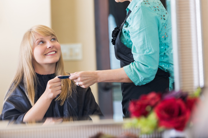 Client paying her stylist at the front desk