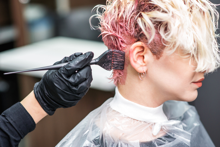 Stylist applying pink hair color with a brush